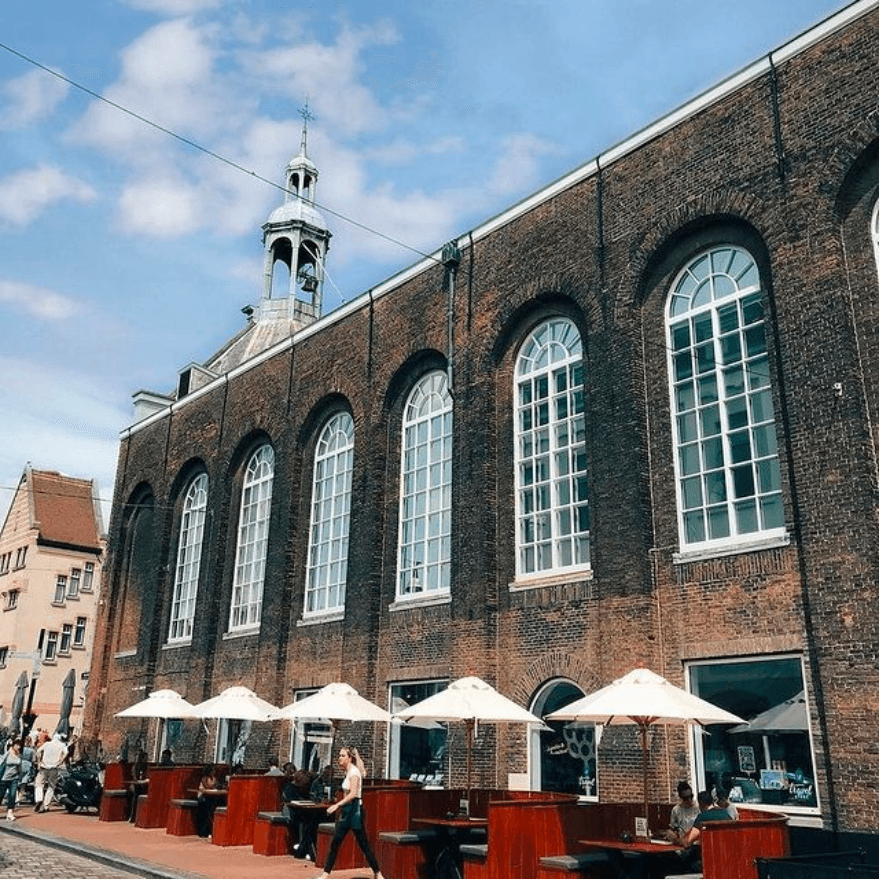 Het monumentale pand van De Crimp aan de Visstraat met het terras onder witte parasols